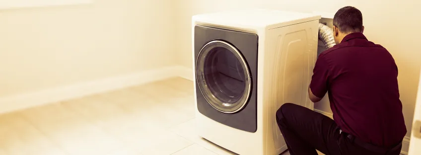 Technician checking the back of a dryer in a laundry room